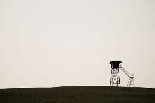 Lonely watch tower. observation post standing alone on the hill. hunting lodge in the field. solitude concept. shelter in the meadow