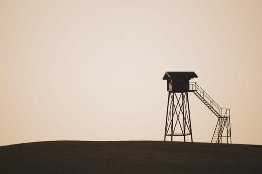 Lonely watch tower. observation post standing alone on the hill. hunting lodge in the field. solitude concept. shelter in the meadow