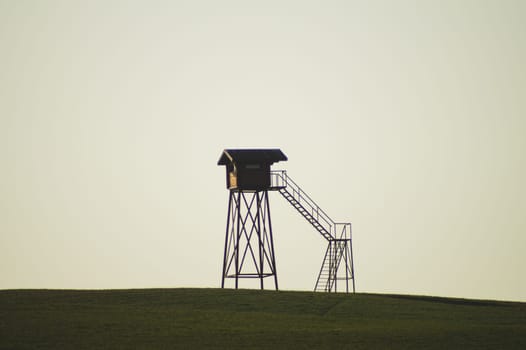 Lonely watch tower. observation post standing alone on the hill. hunting lodge in the field. solitude concept. shelter in the meadow