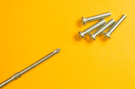 Steel screw on a yellow background. working tools
