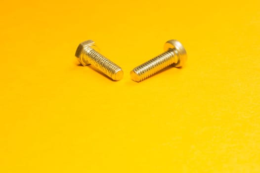 Steel screw on a yellow background. working tools