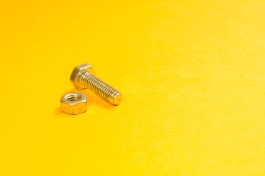 Steel screw on a yellow background. working tools