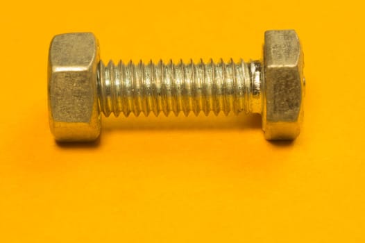 Steel screw on a yellow background. working tools