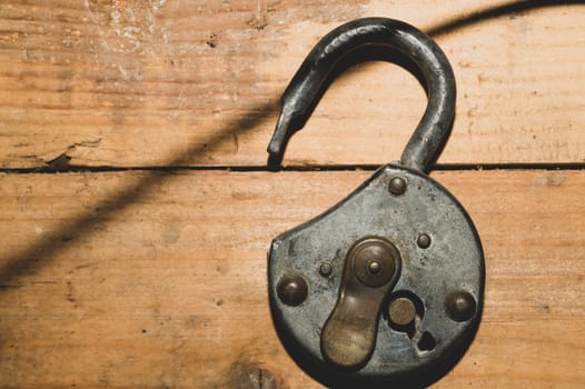 Old rusty lock on a wooden table. Vintage padlock on wood background