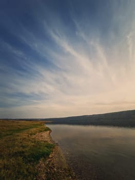 Scenic view to the riverbank of Nistru river, Moldova. Vertical background, calm water flowing. Natural landscape, silent empty place.