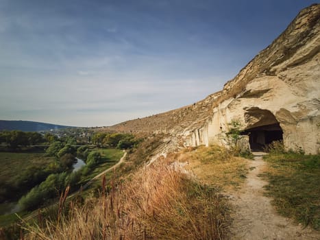 View to the caves of karst limestone hills at Orheiul Vechi, old Orhei complex, near Trebujeni village, Moldova. Autumn season nature landscape alongside Raut river