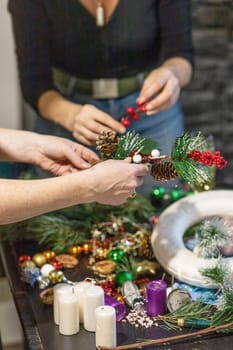 Two women are preparing advent wreath and Christmas decorations. Vertically.