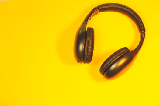 Black headphones on a yellow background. wireless earphones