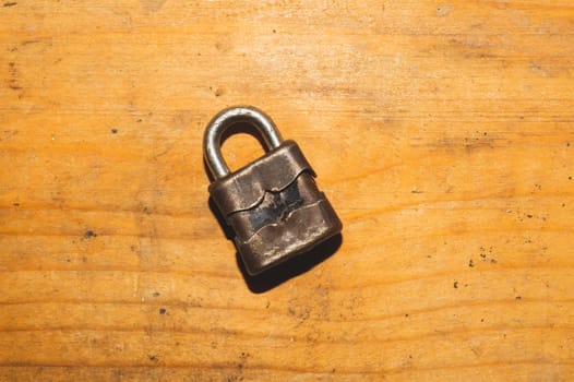 Old rusty lock on a wooden table. Vintage padlock on wood background