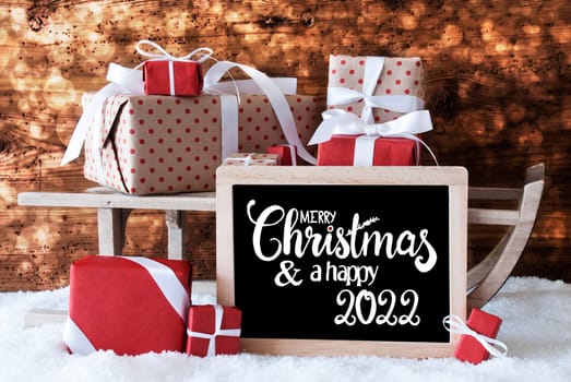 Blackboard With English Calligraphy Merry Christmas And A Happy 2020. Sled With Christmas Gift And Presents. Wooden Background With Snow And Bokeh