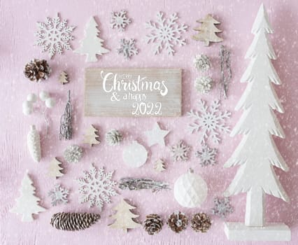 Sign With English Calligraphy Merry Christmas And Happy 2022. Pink Wooden Background. White Christmas Decoration Like Tree, Ball And Snowflakes