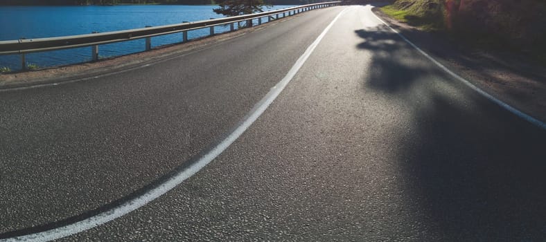 Asphalt road near the lake. low angle. highway at sunset. panoramic view