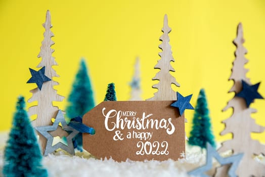 Label With English Text Merry Christmas And Happy 2022. Christmas Trees With Star Decoration And Ornament. Yellow Background With Snow