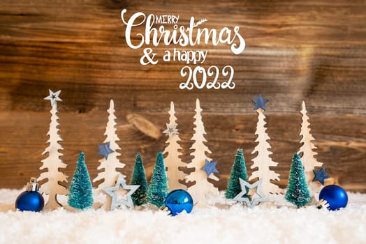 Christmas Trees With English Text Merry Christmas And Happy 2022. Christmas Decoration Like Blue Star Ornament And Balls. Brown Rustic Background With Snow.
