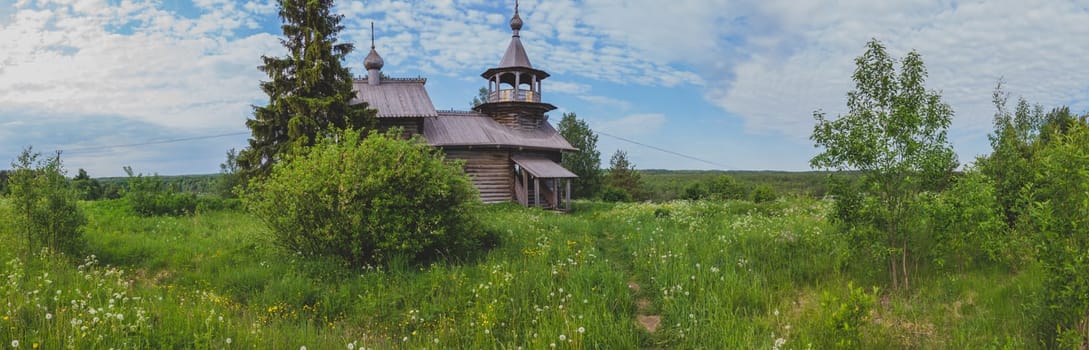 Old wooden church among the overgrown field. rural panoramic landscape