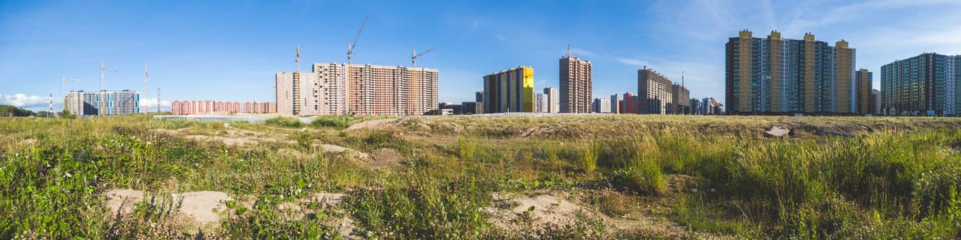 Building construction behind the field. cityscape panorama