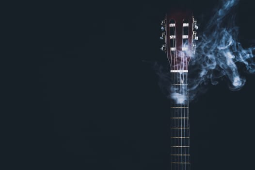 Guitar in smoke on the black background. acoustic musical instrument. strings on the guitar neck