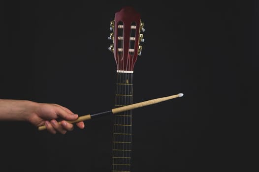 Drumstick in the hand and guitar fretboard close up. acoustic musical instrument. copy space