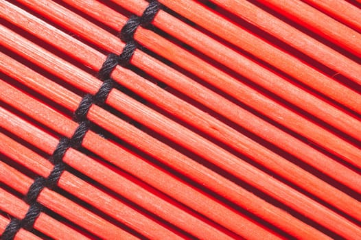 Bamboo mat background close up. wooden backdrop. red wooden sticks bound together