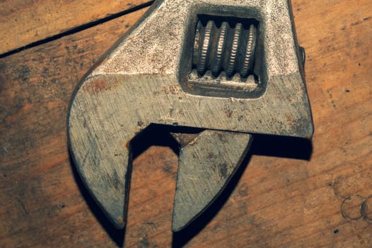 Old adjustable wrench on wood background. working tool. plumbing repairing instrument