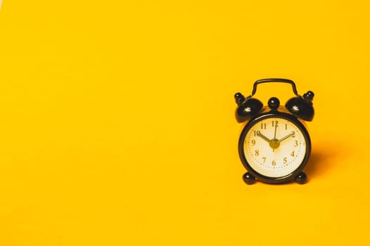 Classic alarm clock on yellow background. vintage watch with round dial. copy space