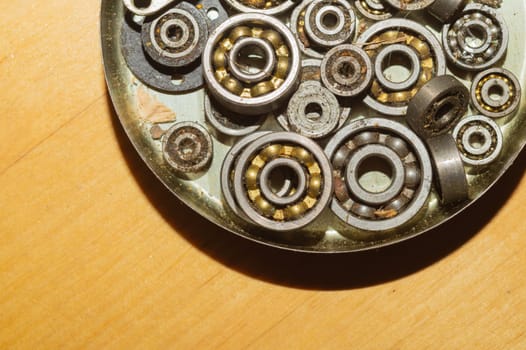 Metal bearings in a box on a wooden background. a lot of gears