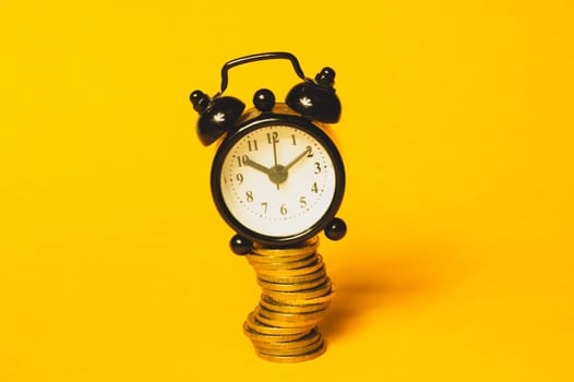 Time is money concept. classic alarm clock with coins on yellow background. vintage watch with round dial. copy space