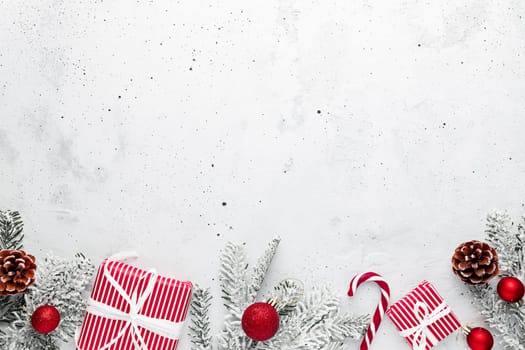 Christmas, New Year gray concrete flat lay. Red white striped present gift boxes top view. Gift ribbon and packaging paper. Christmas tree fir, cones, toy balls, wooden star. Copy space area on photo