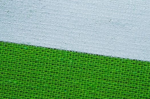 Green fabric texture with white painted place. knitted textile close up. woven background with copy space
