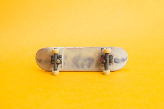 Small skateboard on yellow background. tiny skate for fingers. fingerboard close up. copy space