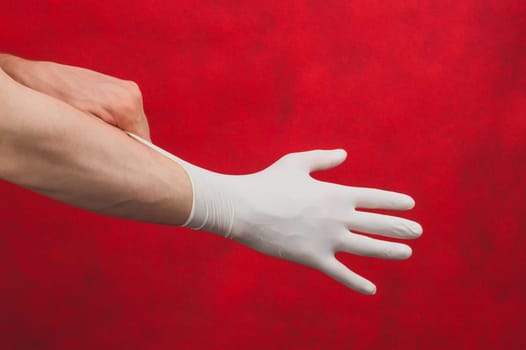 Hand in medical glove. person puts on surgical gloves on a red background