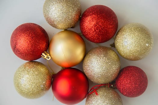 Golden and red Christmas balls with and without sequins lie on a white background. High quality photo