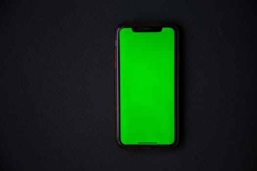The phone with a green screen is on a black background. . High quality photo