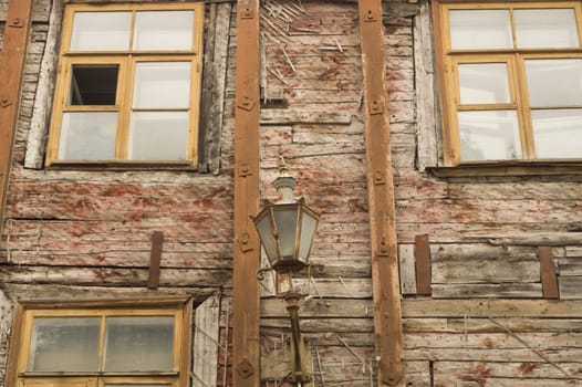 Windows of the old wooden house. wooden plank wall with windows and vintage lamp