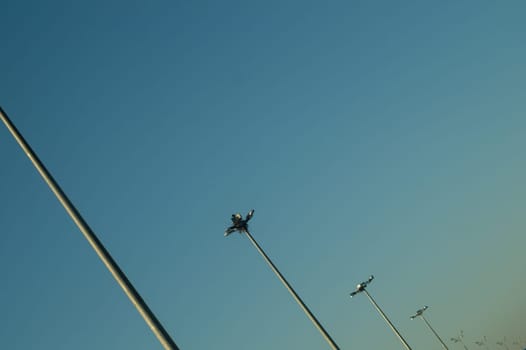 Street lamp posts standing in order on a highway with clear sky background