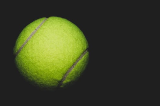 green tennis ball isolated on black background. sport equipment