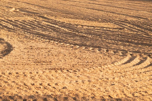 Pattern of curved ridges and furrows on a sandy field. traces on the sand. tractor tracks