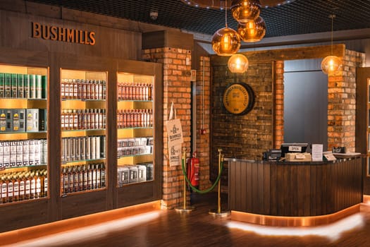 Bushmills, Northern Ireland, Aug 2019 Bushmills whiskey on illuminated shelfs on a display and cash register in distillery visitor centre and shop