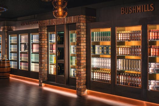 Bushmills, Northern Ireland, Aug 2019 Variety of Bushmills whiskey in a rows on illuminated shelf on a display in distillery visitor centre and shop