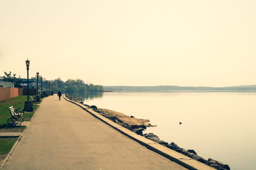 Coastline of the lake at evening. man walking on the promenade