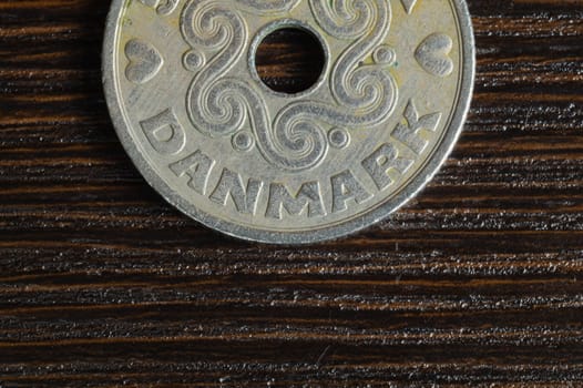 Danish coin on a dark wooden background. krone from Denmark close up. coin with hole