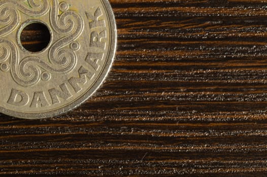 Danish coin on a dark wooden background. krone from Denmark close up. coin with hole
