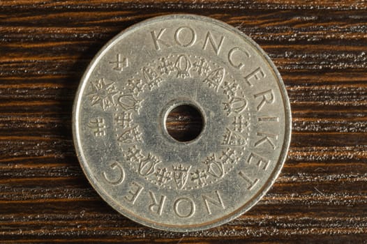 Norwegian coin on a dark wooden background. krone from Norway close up. coin with a hole