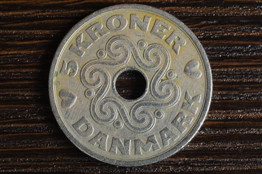 Danish coin on a dark wooden background. krone from Denmark close up. coin with hole