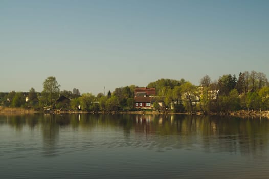 Lake house. house on the shore in the village. countryside landscape with reflection on the water