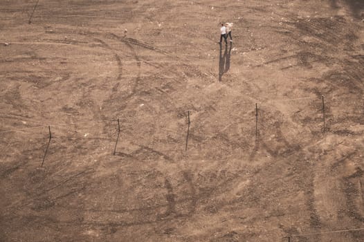 Couple walking on the sand in sunny day. aerial view. ground with tracks and footprints. view from above of a couple of tourists. conceptual background with copy space