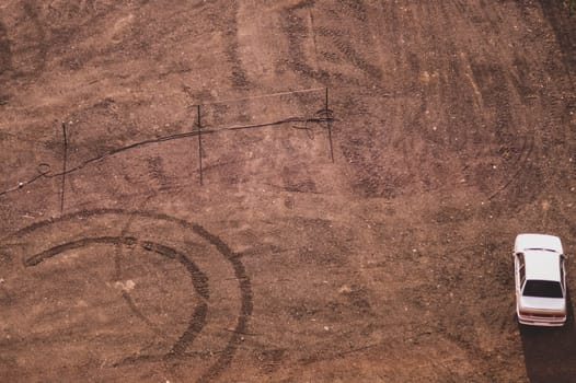 Car stands on the sand aerial view. ground with tracks and footprints. conceptual background with copy space