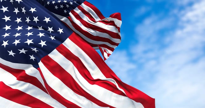 Two flags of the United States of America waving in the wind. Clear sky in the background. Selective focus. Democracy, independence and election day. Patriotic symbol of American pride