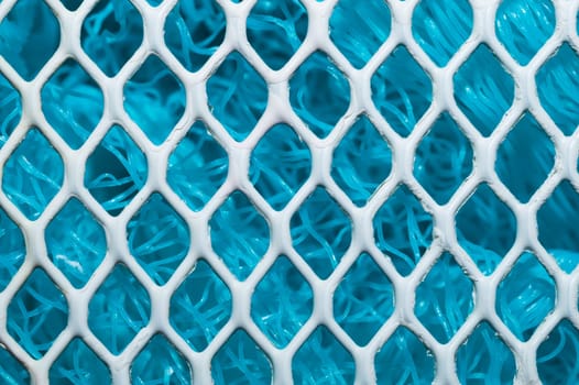 Metal enameled grid. abstract background. blue cloth behind the metallic grate. iron white mesh