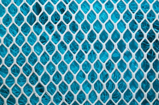 Metal enameled grid. abstract background. blue cloth behind the metallic grate. iron white mesh